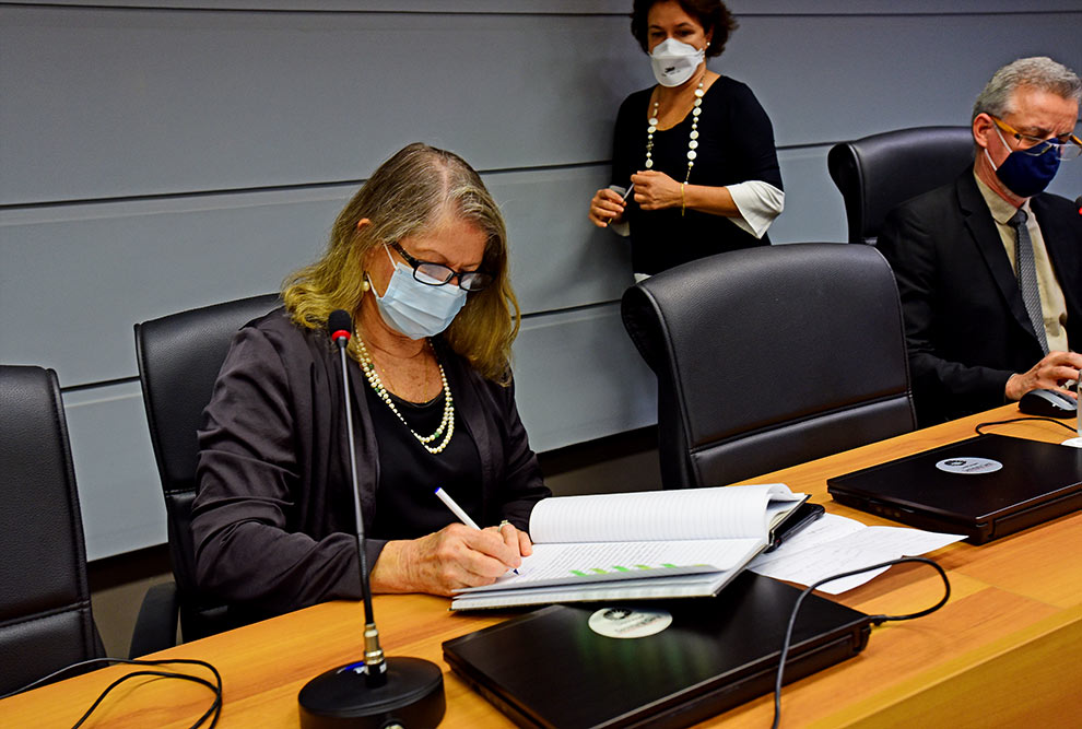 foto mostra maria luiza moretti, coordenadora geral da unicamp, assinando o termo de posse na sala do consu